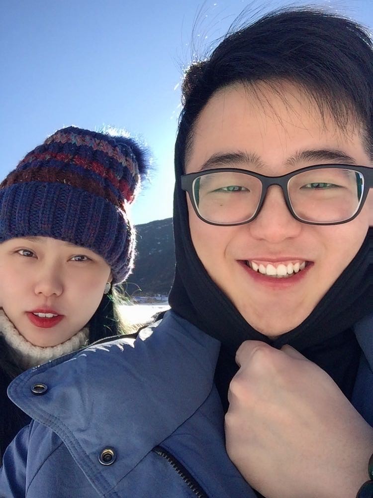 情侣旅行照片，站在海边夕阳下，两人手牵手背影，天空呈现橙红色晚霞